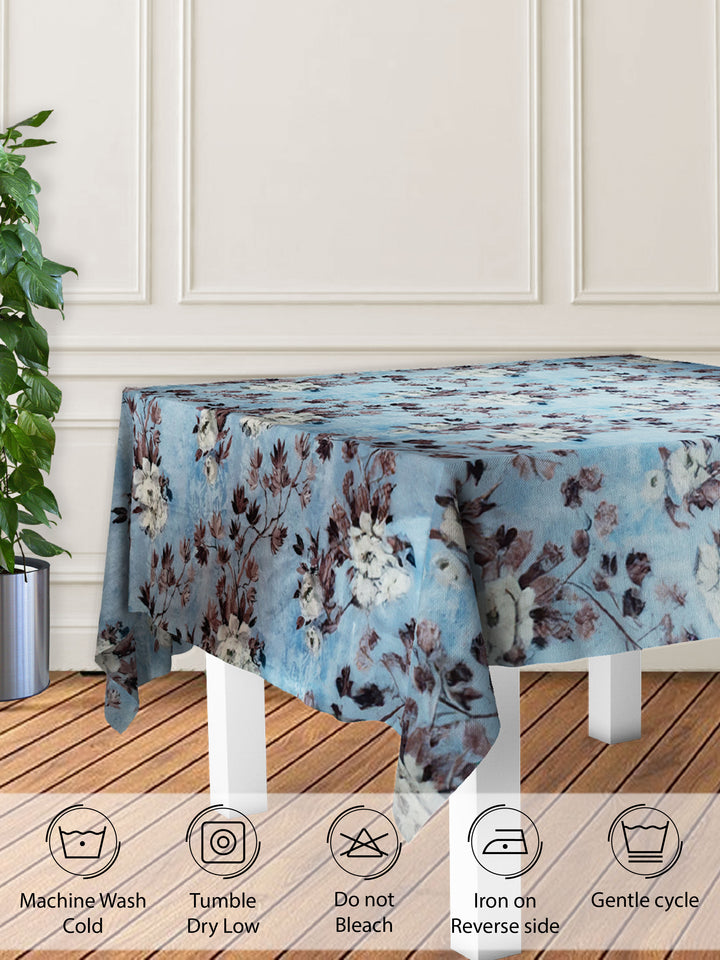 Floral patterned tablecloth on a wooden table with care instructions displayed.