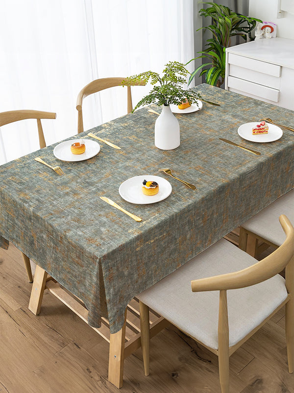 Dining table set with a patterned tablecloth, plates, and cutlery in a bright room.