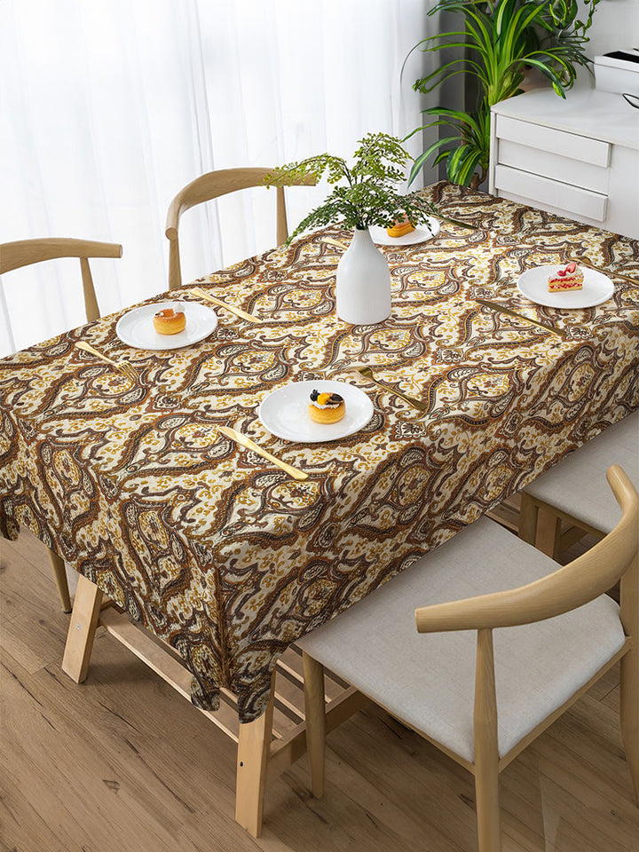 Dining table with a patterned tablecloth, chairs, and small plates with food.