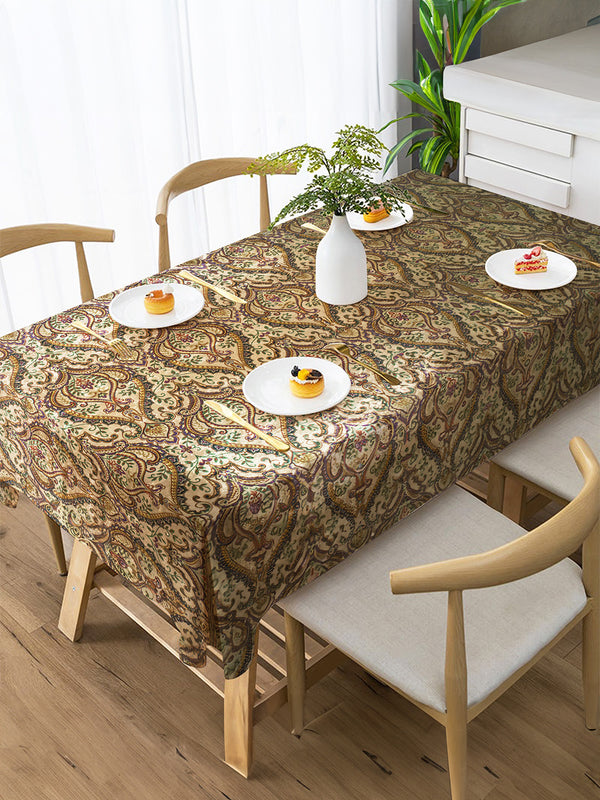 Dining table with a patterned tablecloth, plates with food, and chairs in a room.
