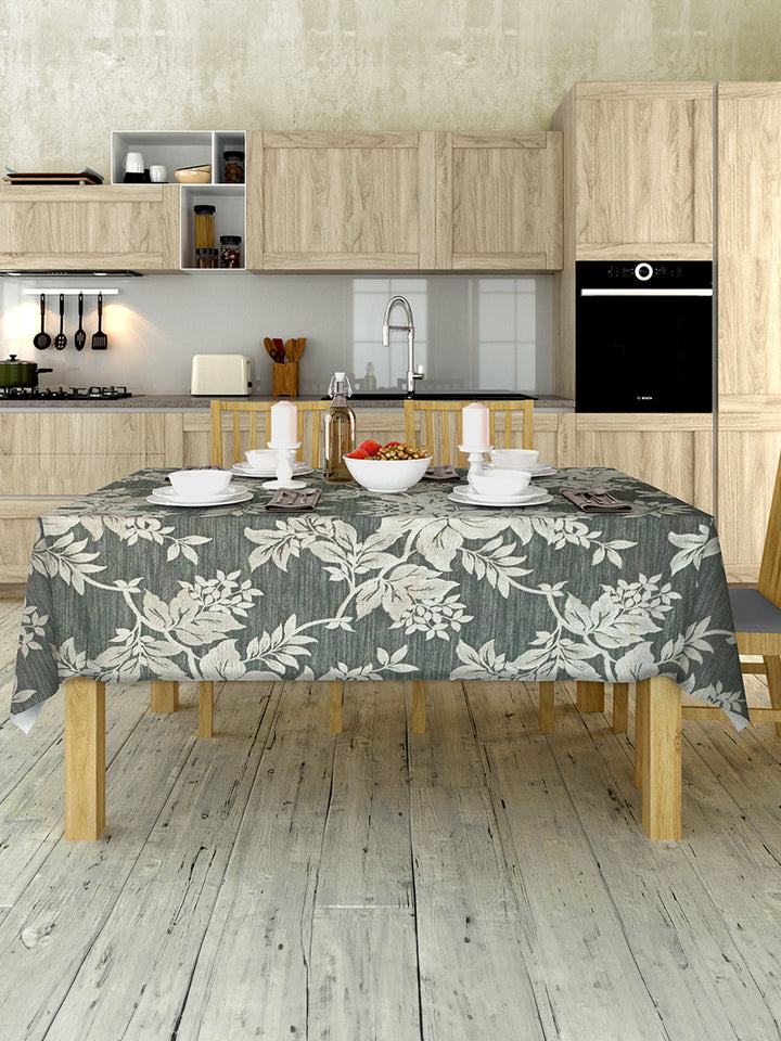 Kitchen with wooden cabinets, a floral tablecloth on a table, and various kitchen items.