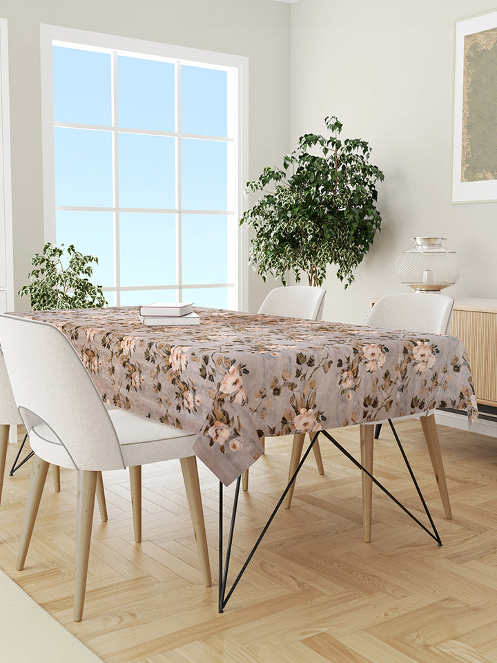 Dining room with a floral tablecloth on a table and white chairs.