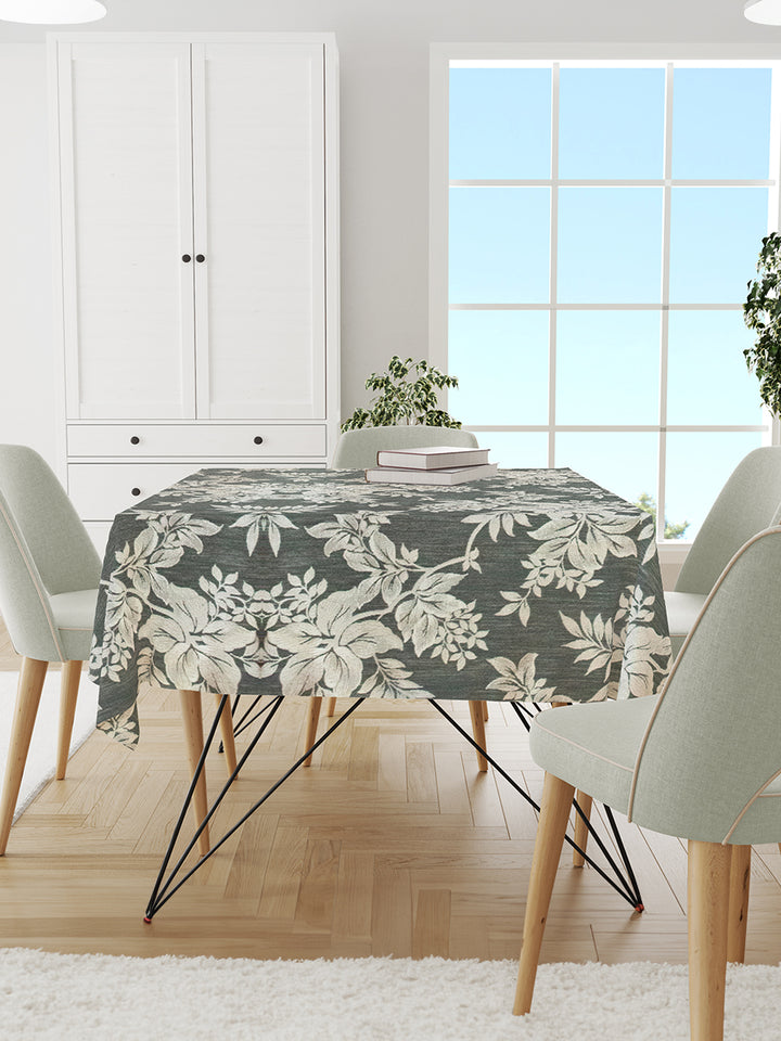 Dining room with a floral tablecloth on a table, white chairs, and a large window.