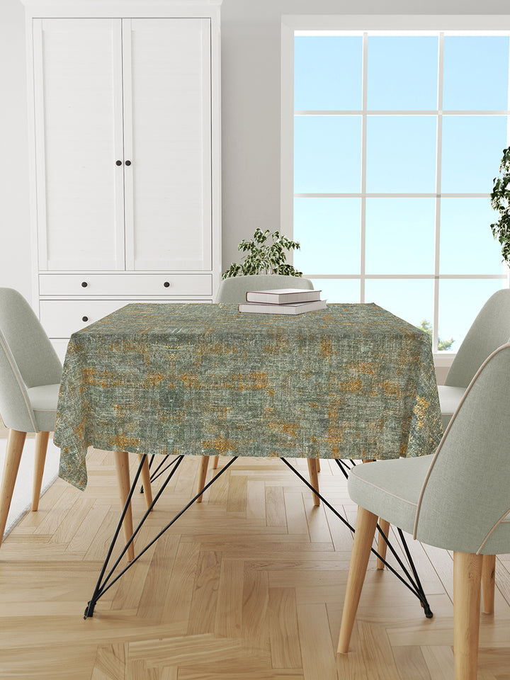 Dining room with a table covered by a patterned tablecloth, chairs, and a window in the background.