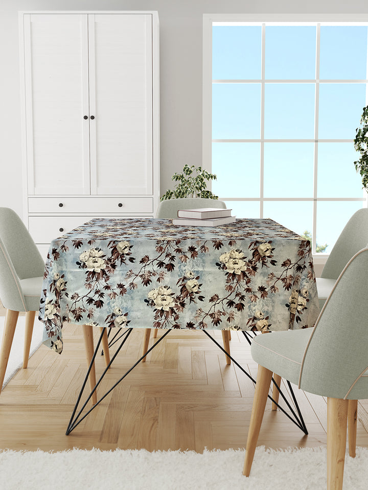 Dining room with a floral tablecloth on a table, chairs, and a cabinet.