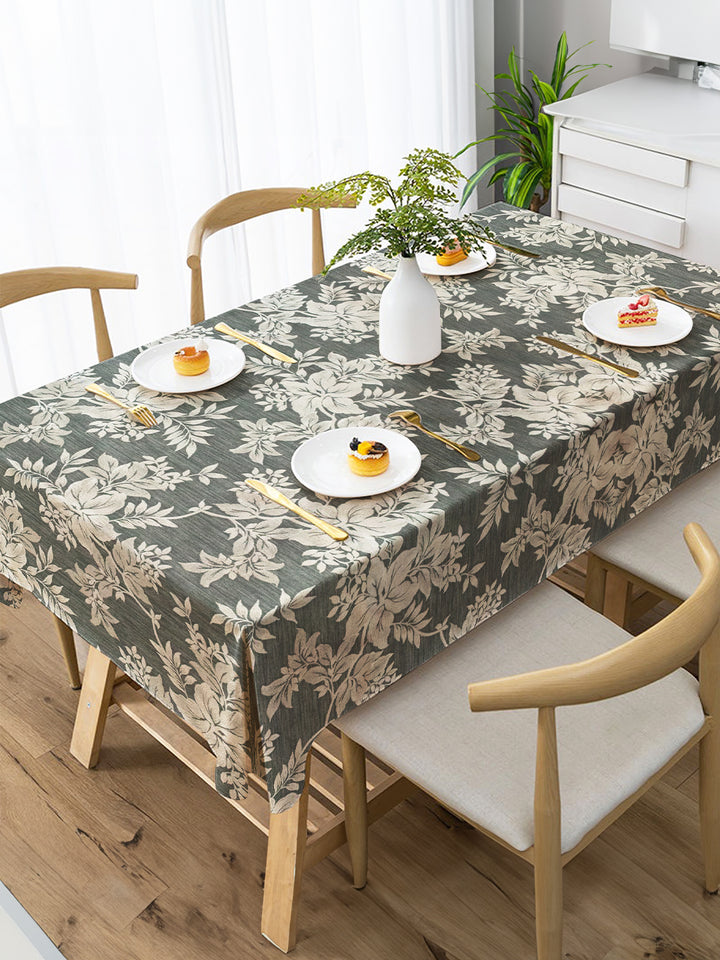 Dining table with floral-patterned tablecloth, chairs, and small plates with food.