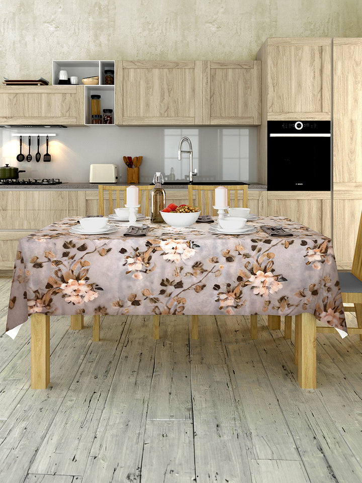 Kitchen with wooden cabinets, a table covered with a floral tablecloth, and various kitchen items.