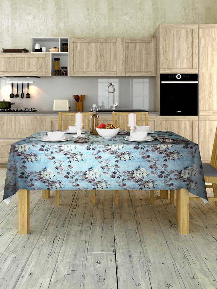 Kitchen with wooden cabinets, a floral tablecloth on a table, and various kitchen items.