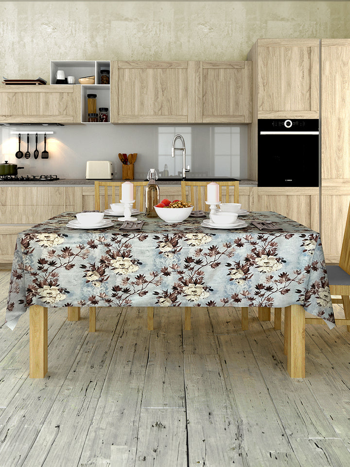 Kitchen with wooden cabinets, a table with a floral tablecloth, and various kitchen items.