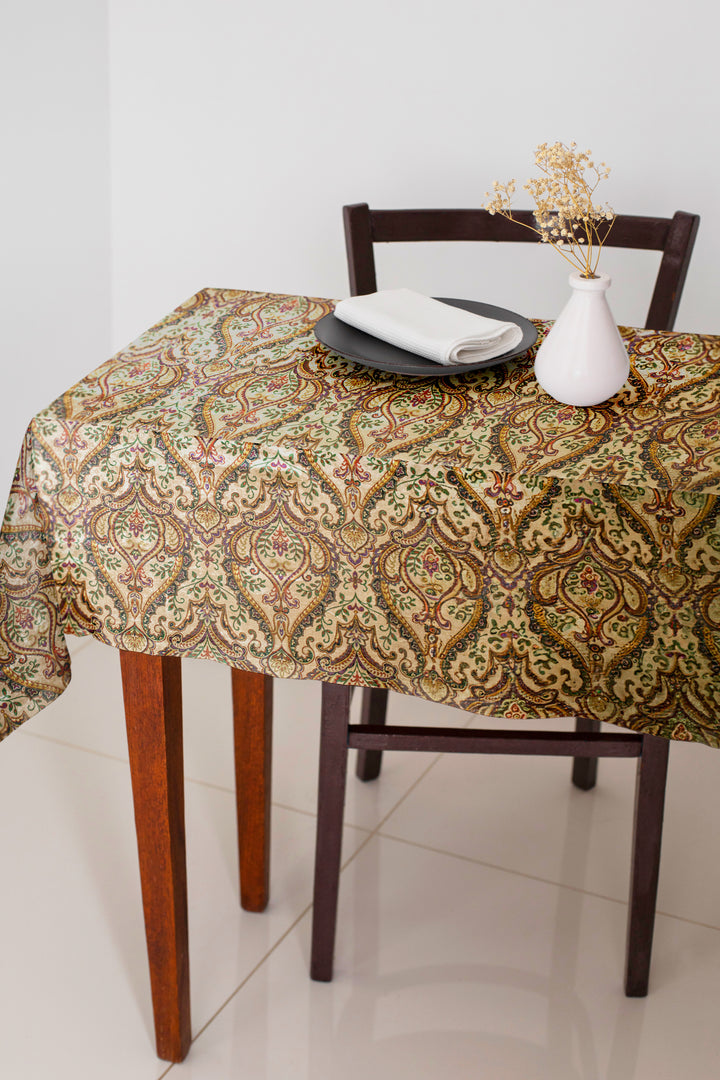 Table with a patterned tablecloth, chairs, and a vase on a tiled floor.