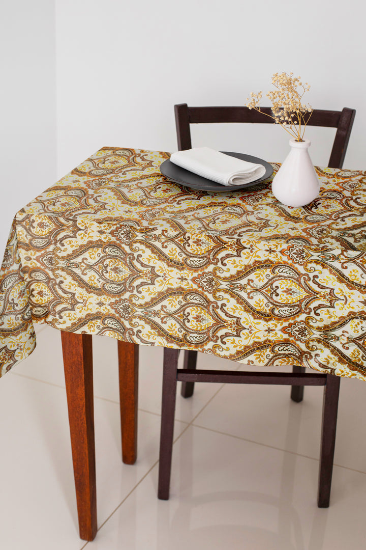 Dining table with a patterned tablecloth, chair, and decorative items on a tiled floor.