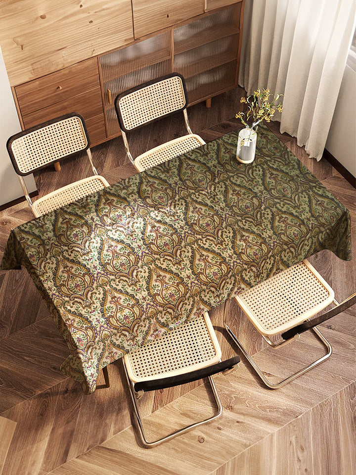 Table with a patterned tablecloth and four chairs in a room with wooden flooring and furniture.