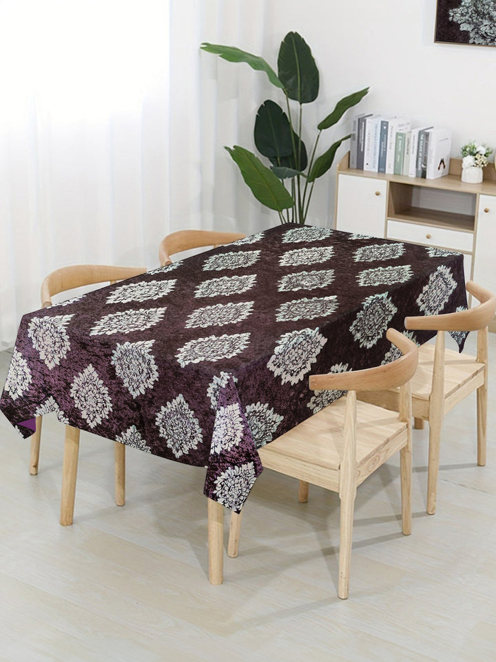 Table with a patterned tablecloth in a room with chairs and decor.