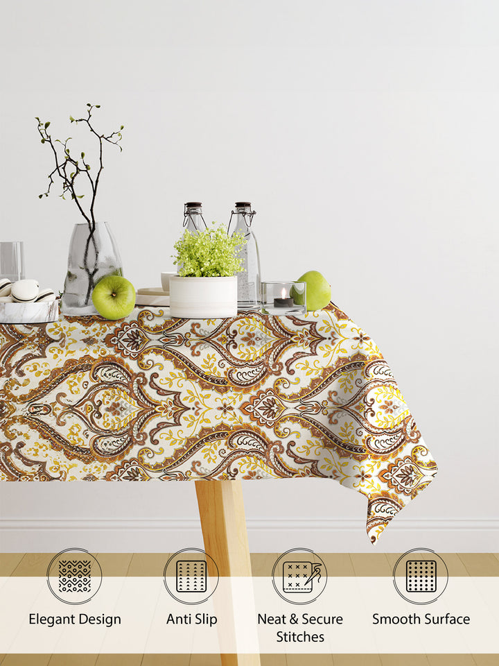 Patterned tablecloth on a table with decorative items against a white wall.