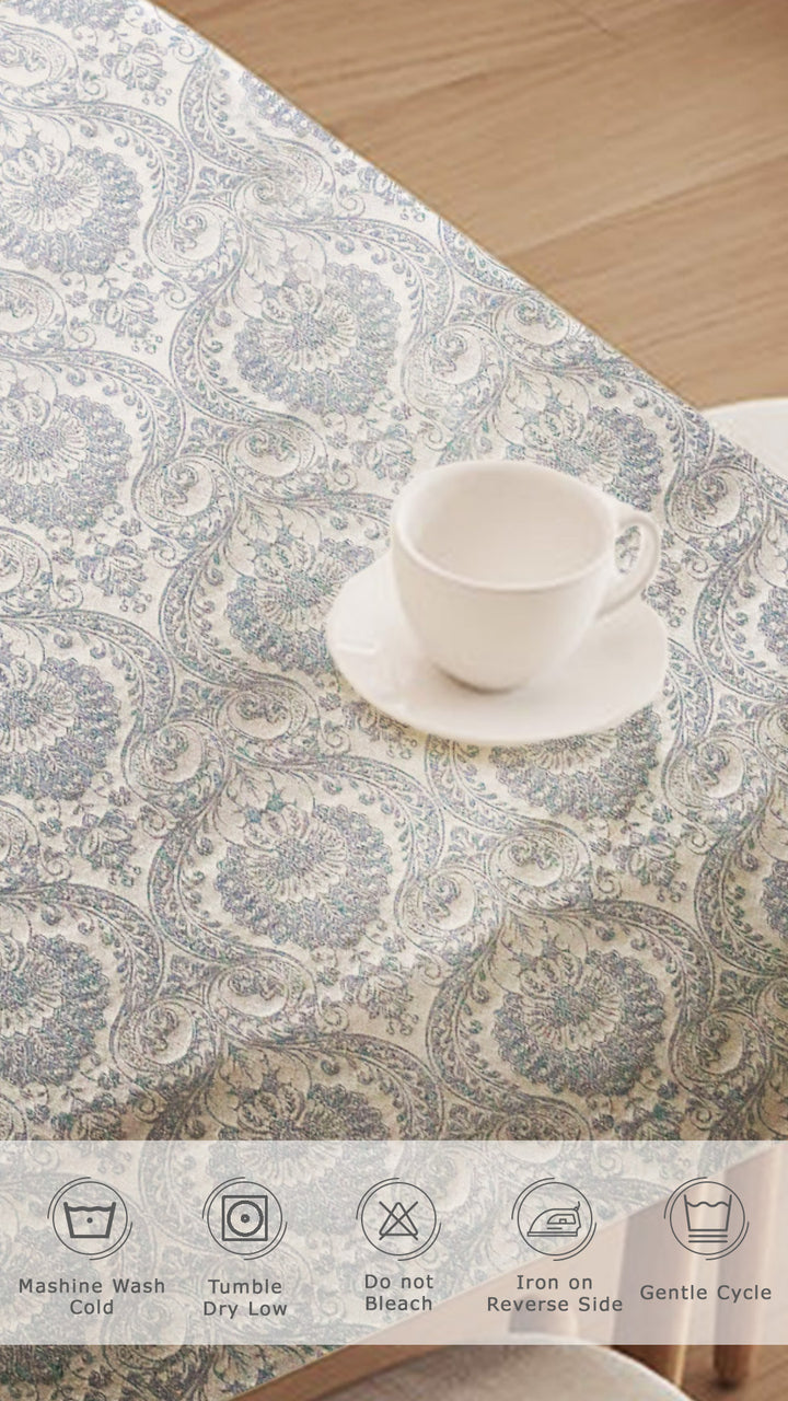 Tablecloth with paisley pattern on a wooden table with a cup and saucer.
