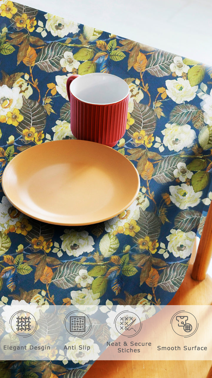 Table setting with a floral tablecloth, red mug, and yellow plate on a white background.