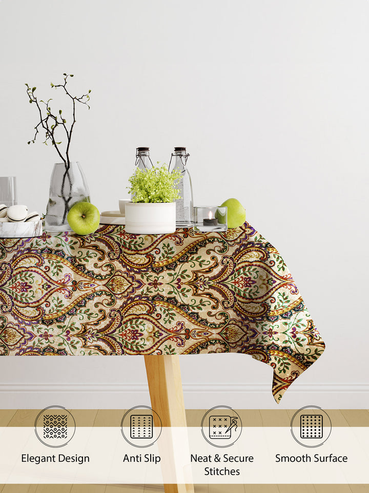 Decorative tablecloth with paisley pattern on a table with apples and a plant.