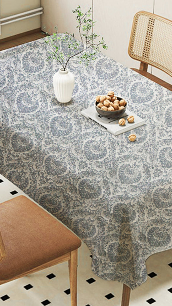 Tablecloth with a pattern on a dining table with chairs and decor items.