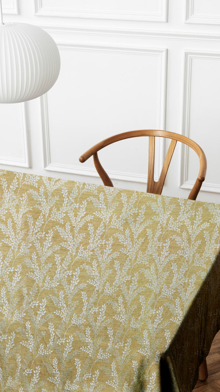 Tablecloth with floral pattern on a table against a white paneled wall.