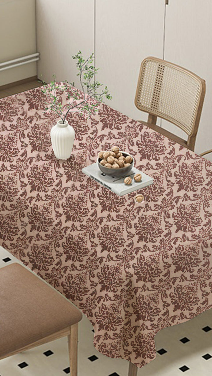 Table with a patterned tablecloth, vase, and bowl on a checkered floor.