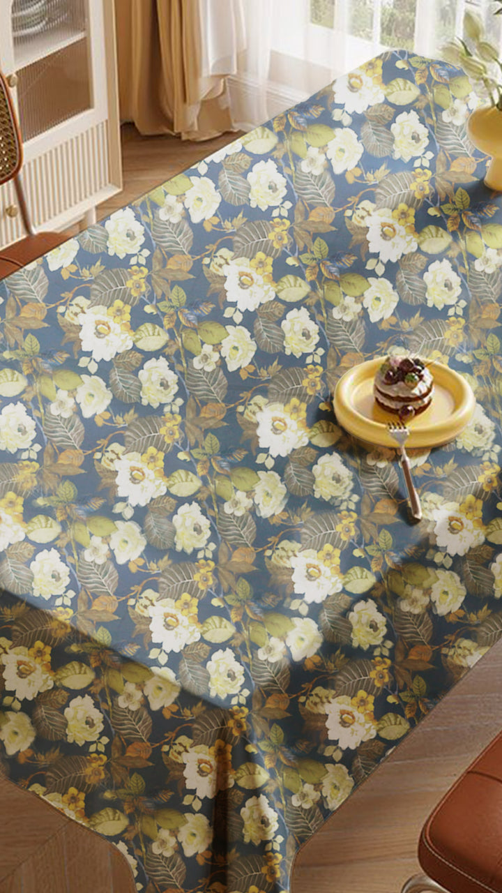 Floral-patterned tablecloth on a dining table with a cake and spoon.