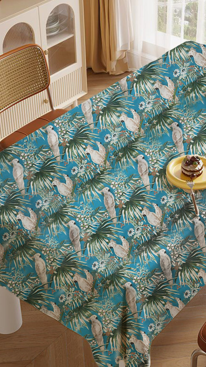 Tablecloth with tropical design featuring parrots and palm trees on a table.