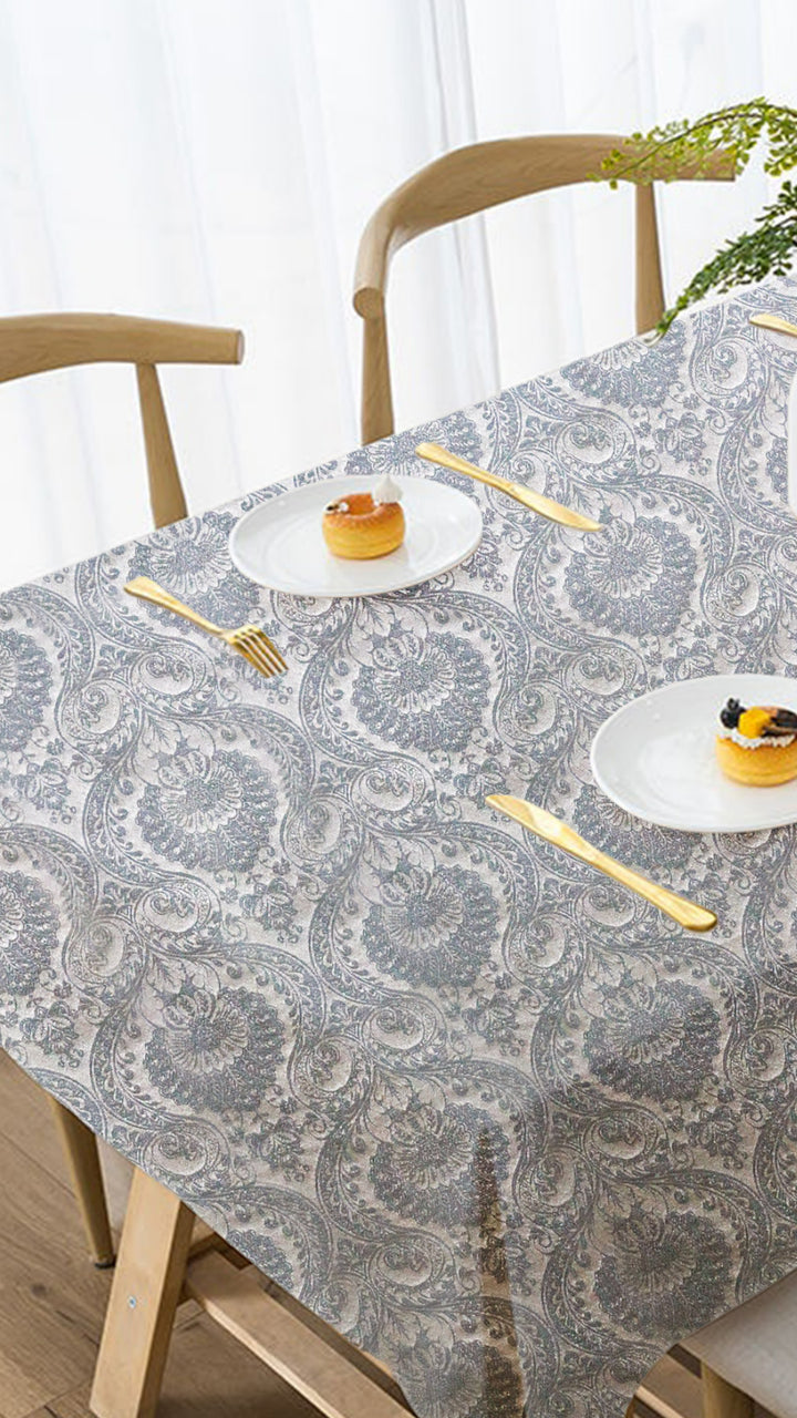 Dining table with a patterned tablecloth, plates, and cutlery.