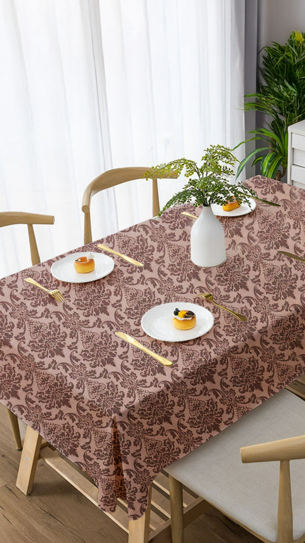 Table setting with a patterned tablecloth, plates, and cutlery in a dining room.