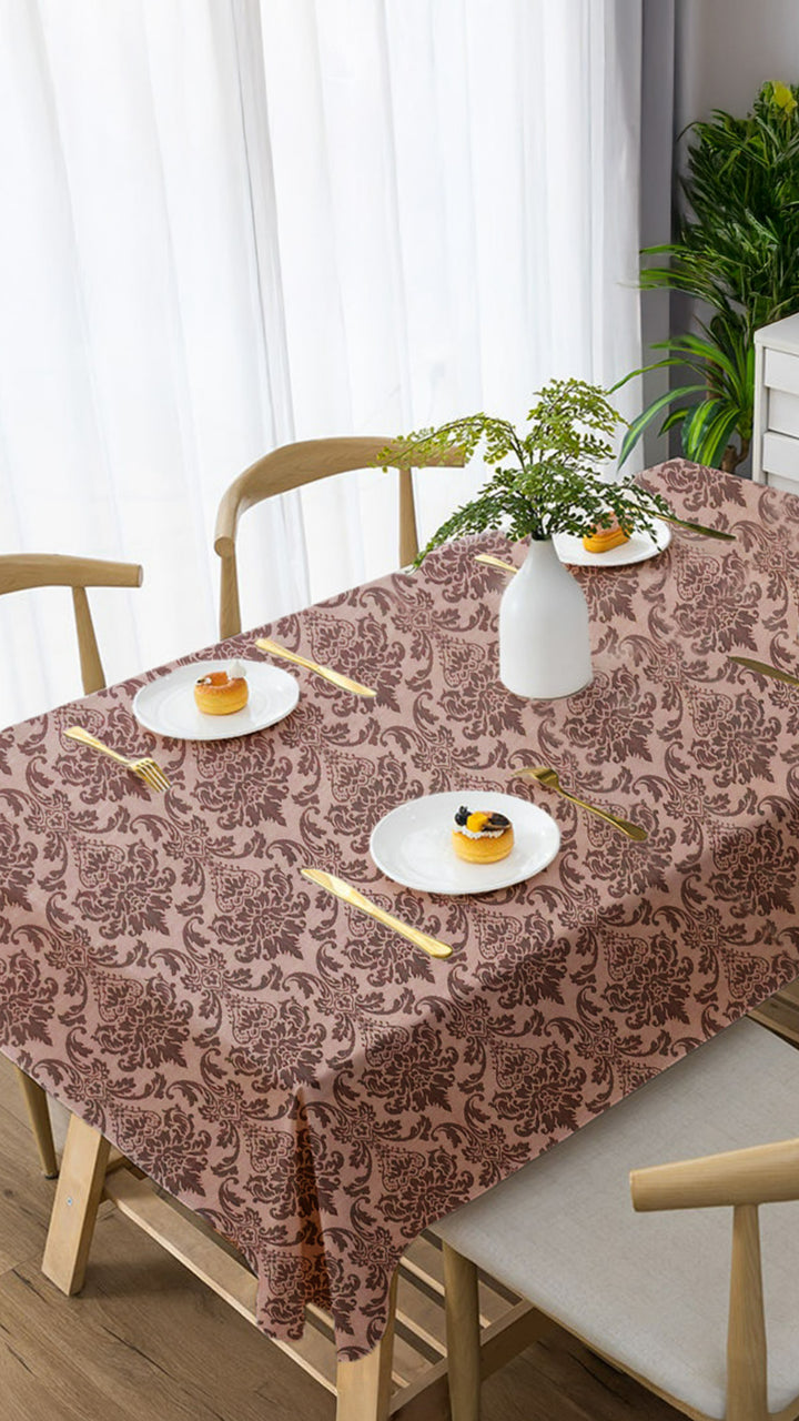 Table setting with a patterned tablecloth, plates, and cutlery in a dining room.