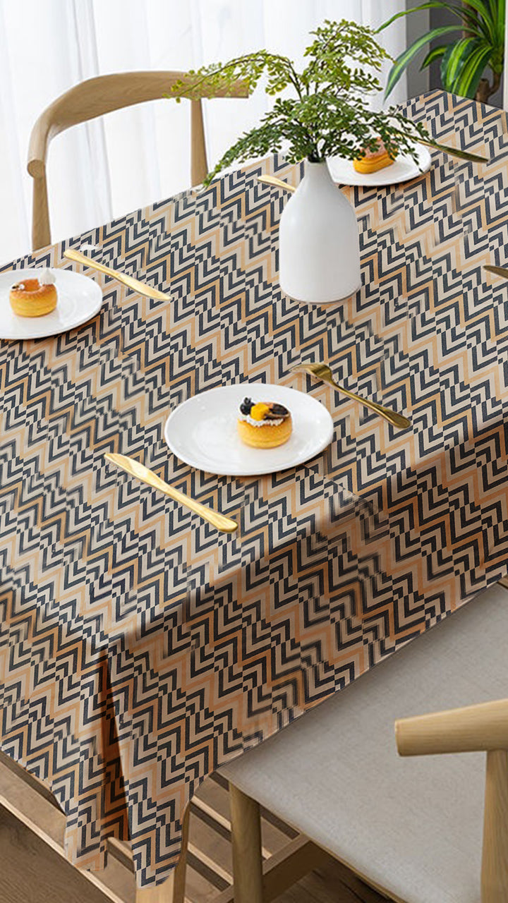 Table with a geometric patterned tablecloth, white plates with pastries, and a vase with greenery.