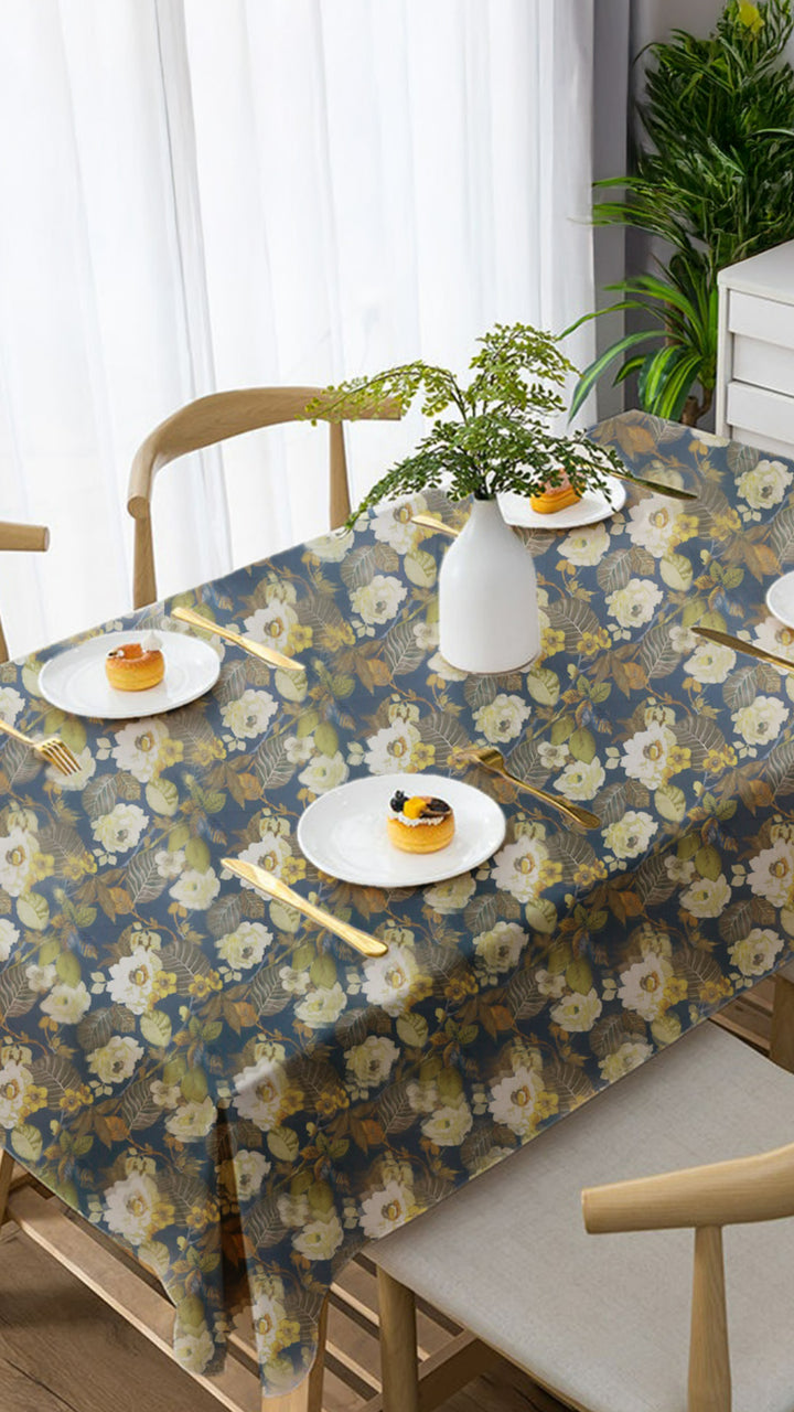 Dining table with floral tablecloth, plates with food, and chairs in a room.